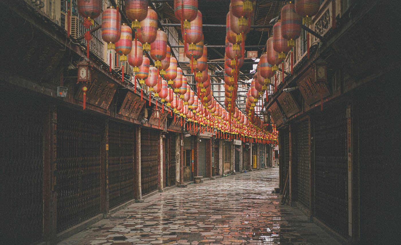 Ruelle pavée la nuit sous des rangées de lanternes rouges